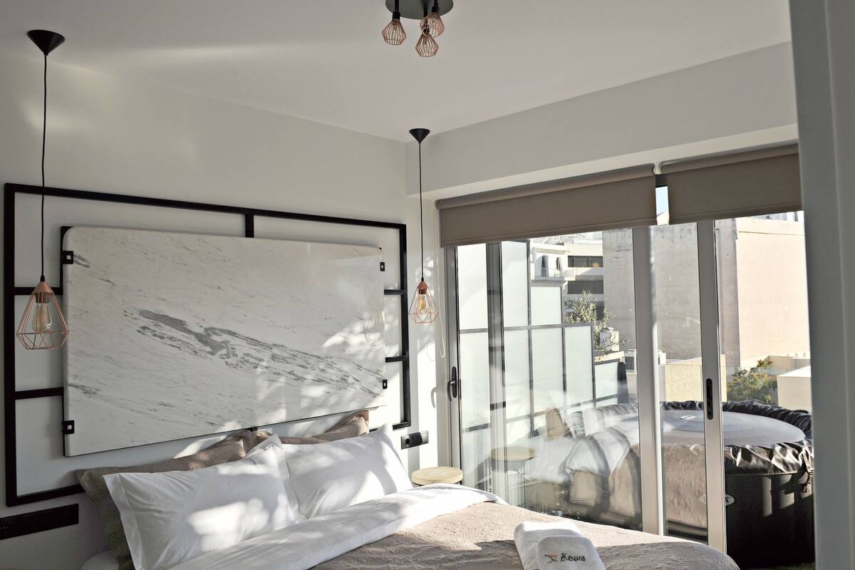 A modern bedroom with a large bed, a marble headboard, and a balcony with a view.