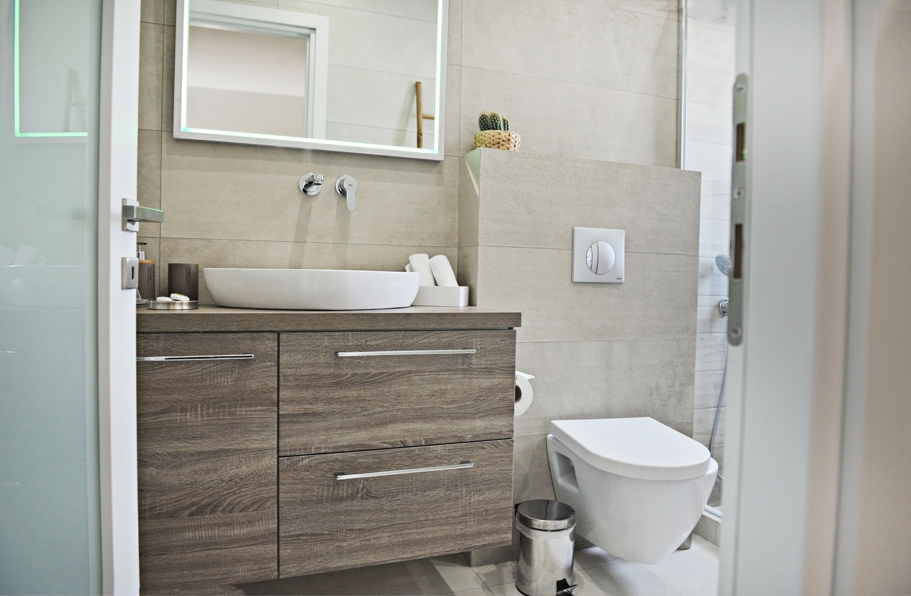 A modern bathroom with a large sink, wooden vanity, and a toilet.