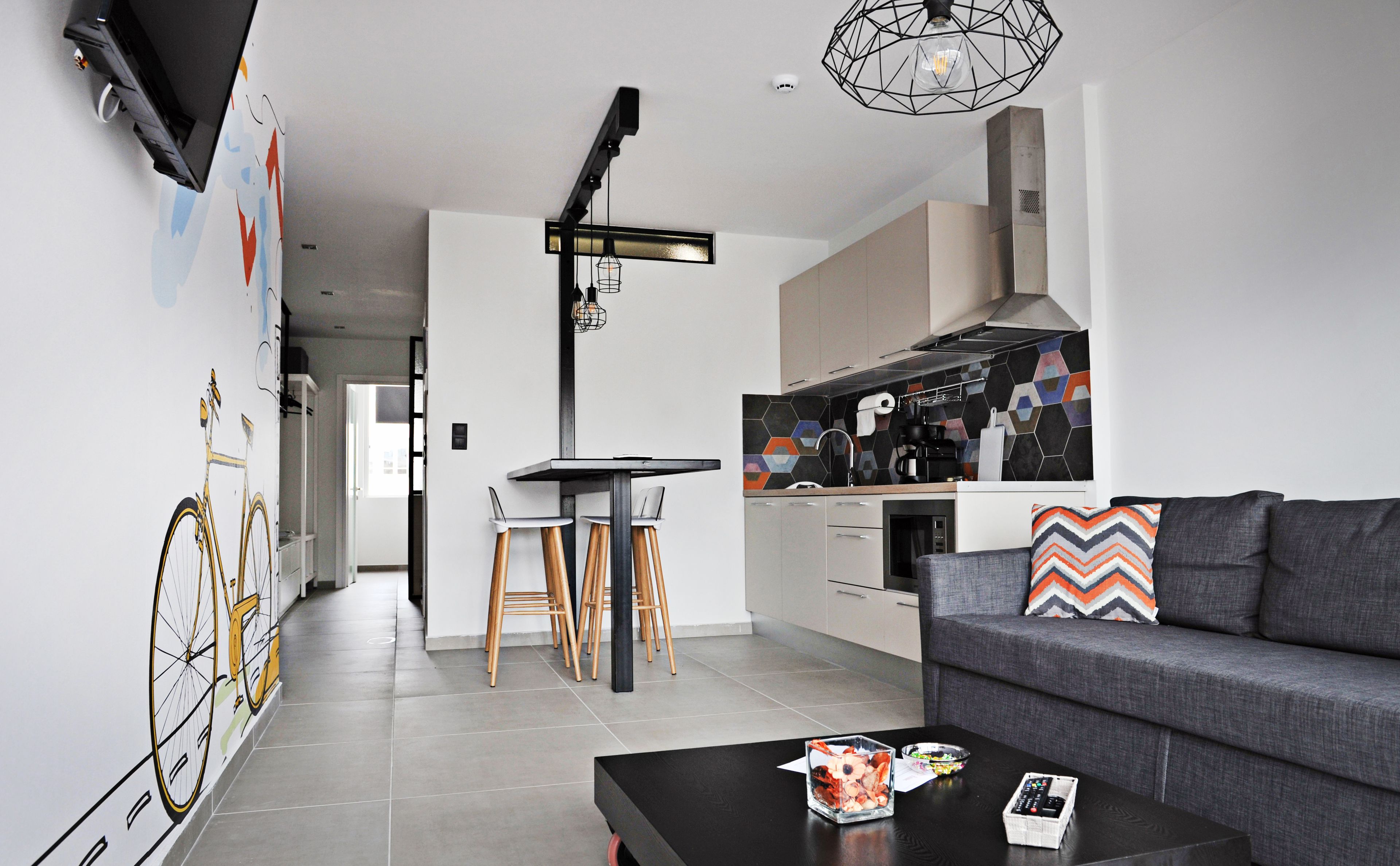 Eine moderne Küche mit schwarzem Arbeitsplatz, integriertem Herd und farbenfroher Spritzschutzwand.