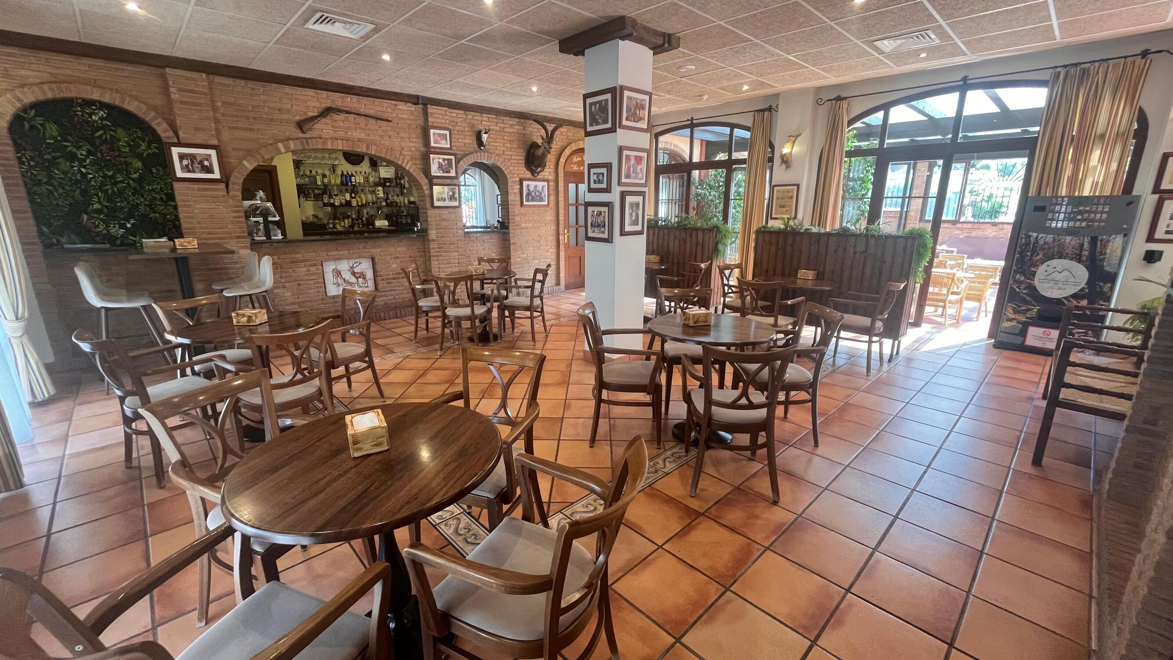 Un restaurante con paredes de ladrillo, mesas y sillas de madera, y cuadros en las paredes.