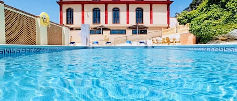 Una piscina al aire libre de temporada, sombrillas