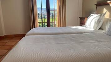 Un dormitorio con dos camas, un ventanal con cortinas y vistas al exterior.