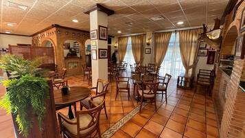 A restaurant with a tiled floor, wooden furniture, and a brick wall.
