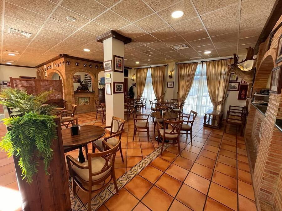 A restaurant with a tiled floor, wooden furniture, and a brick wall.
