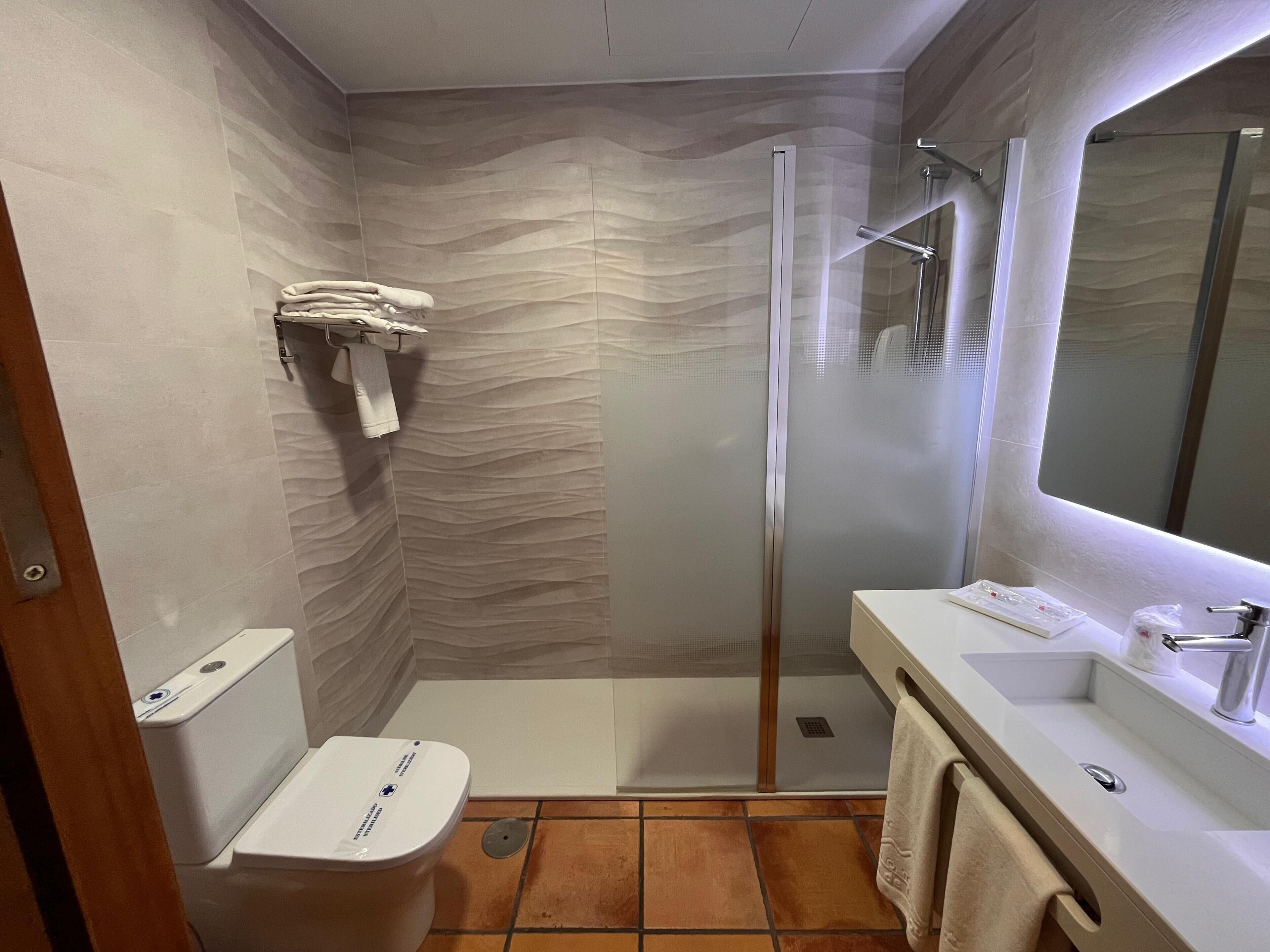 A modern bathroom with a shower, toilet, and sink.