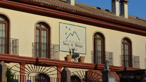 Un edificio con un letrero que dice "Hotel Sierra de Ubrique" e incluye un gráfico de montañas.