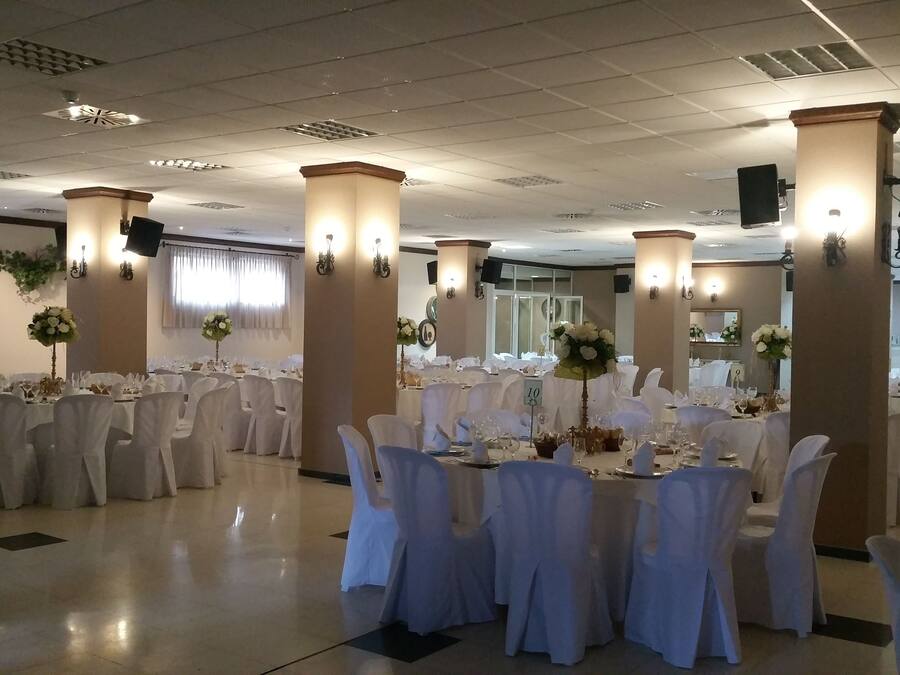 A banquet hall with round tables, white tablecloths, and chairs.