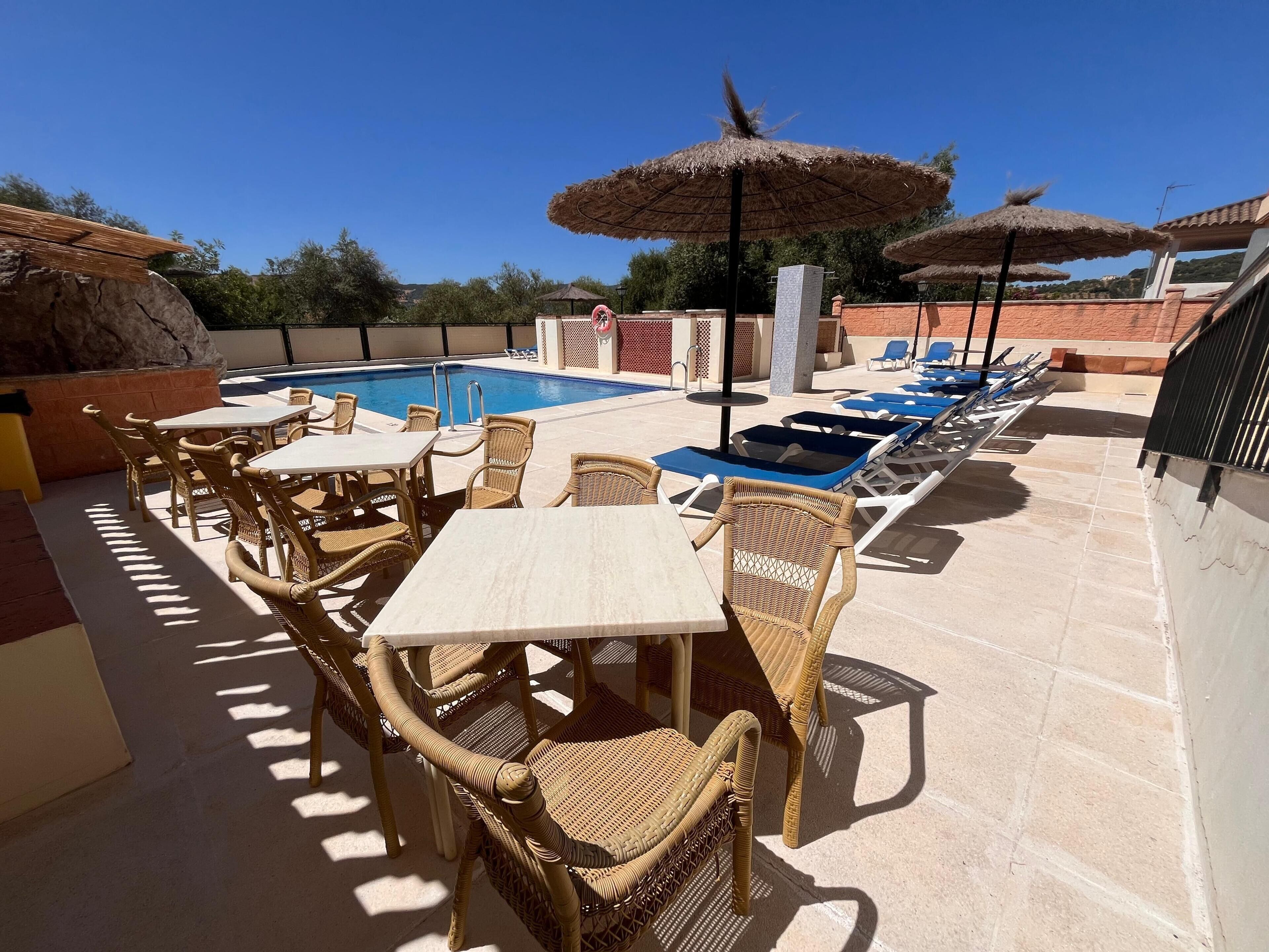 A poolside area with lounge chairs, tables, and umbrellas.