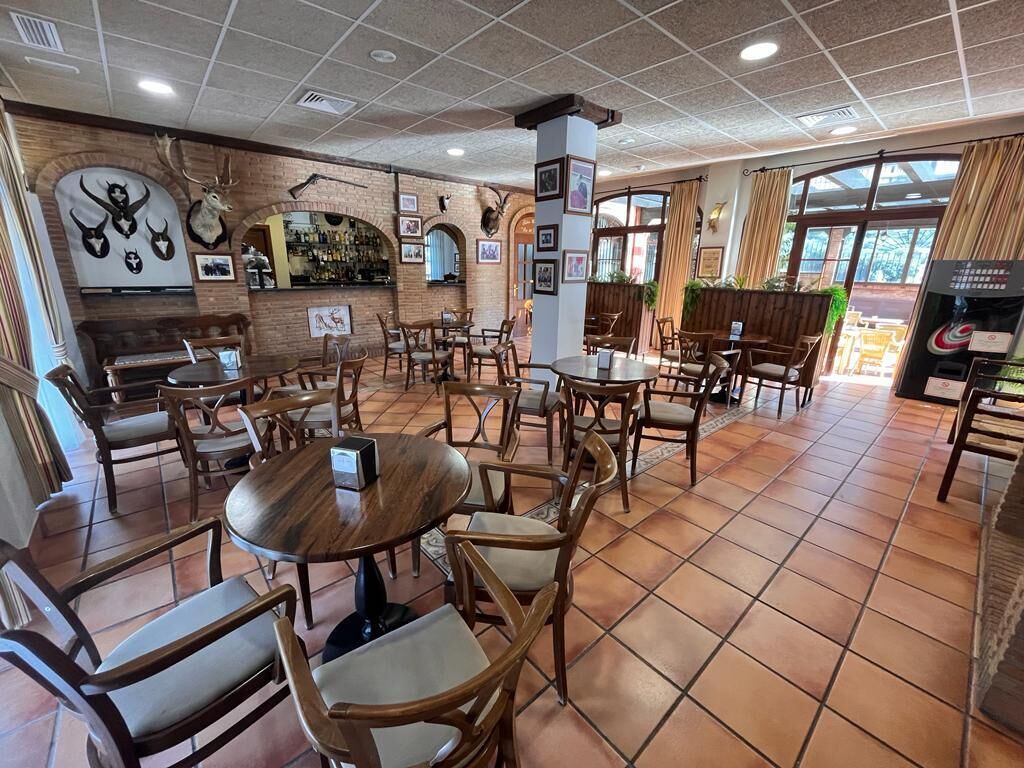 Un restaurante con mobiliario de madera, una pared de ladrillo adornada con trofeos de animales y una zona de bar.