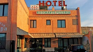 A hotel with a sign for 'Ristorante Pizzeria Rosa' and a car parked in front. - Rosa Hotel (Capoterra)