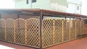 A covered outdoor area with a wooden lattice fence. - Rosa Hotel (Capoterra)
