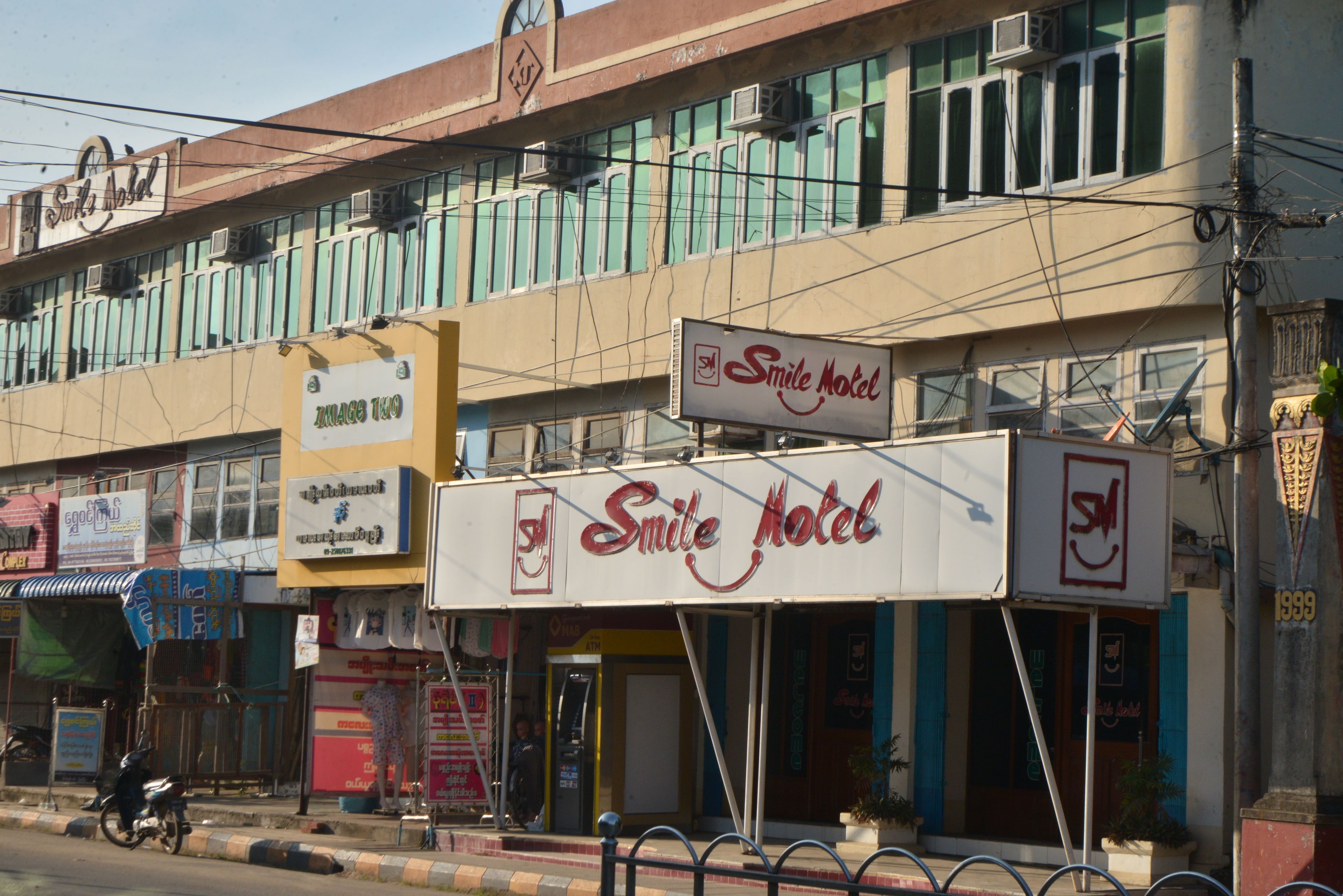 A building with a prominent 'Smile Hotel' sign, multiple air conditioning units, and a variety of storefronts.