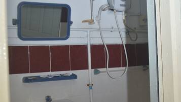 Baño con lavamanos, espejo y cabezal de ducha de mano.