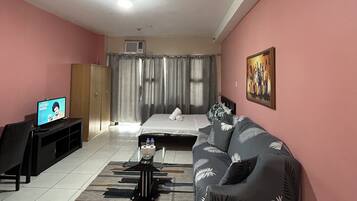 Una habitación con una cama, un sofá, un televisor y un cuadro en la pared.