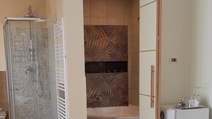 Ein Hotelzimmer mit Bett, Dusche, Badewanne und einer kleinen Küchenzeile.