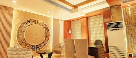 A modern interior with a round decorative wall, two sofas, a dining table, and a built-in air conditioning unit.