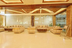 A spacious lobby with a modern design, featuring sofas, a coffee table, and a large window. - Hotel Silk City (Varanasi)