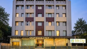 Un hotel de varios pisos con fachada moderna, que presenta una combinación de estilos de ventanas y una entrada destacada con puerta de vidrio.