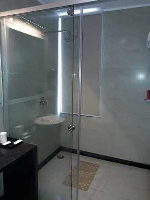 Un baño moderno con ducha de vidrio, lavamanos y espejo.