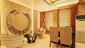 A modern living room with a round decorative wall, two sofas, a coffee table, and a wall-mounted air conditioner. - Hotel Silk City (Varanasi)