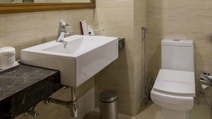 Un baño moderno con un espejo grande, un lavabo blanco, un inodoro y una zona de ducha.