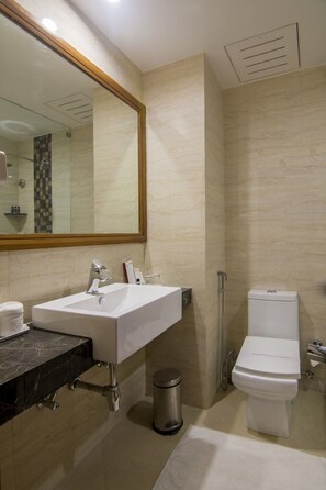 Un baño moderno con un espejo grande, un lavabo blanco, un inodoro y una zona de ducha.