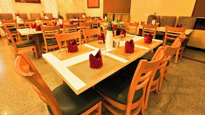 A restaurant with multiple tables and chairs, arranged in a spacious layout. - Hotel Silk City (Varanasi)