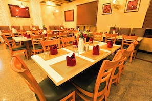 A restaurant with multiple tables and chairs, arranged in a spacious layout. - Hotel Silk City (Varanasi)