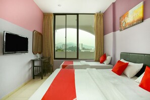 A hotel room with two beds, a TV, a desk, and a large window with a view of buildings and mountains. - Hotel O Ferringhi Stay Iinn (George Town)