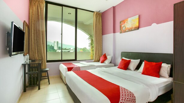 A hotel room with two beds, a TV, a desk, and a window with a city view. - Hotel O Ferringhi Stay Iinn (George Town)