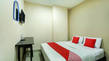A hotel room with a bed, a desk, a chair, a television, and a mirror.