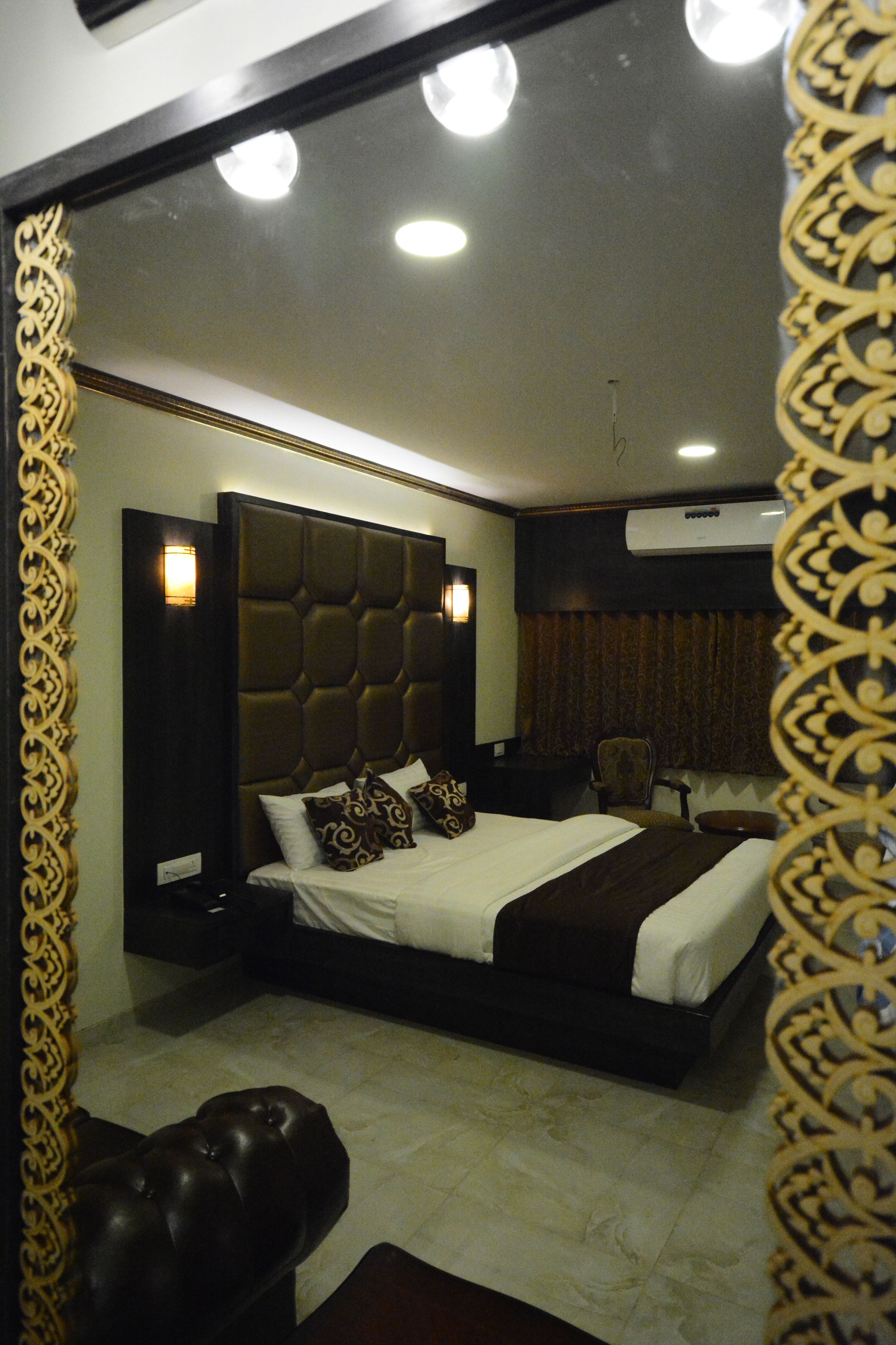 A modern bedroom with a large bed, a headboard, a bedside table, a chair, and a mirror.