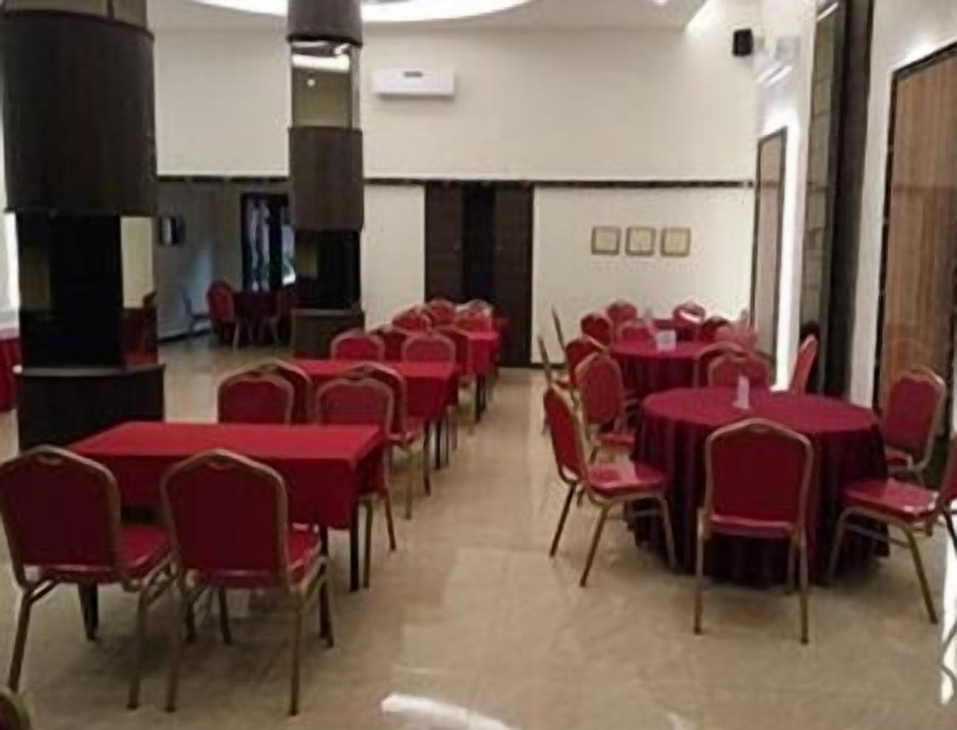 A conference room with rows of tables and chairs, a large pillar, and a door with a sign.