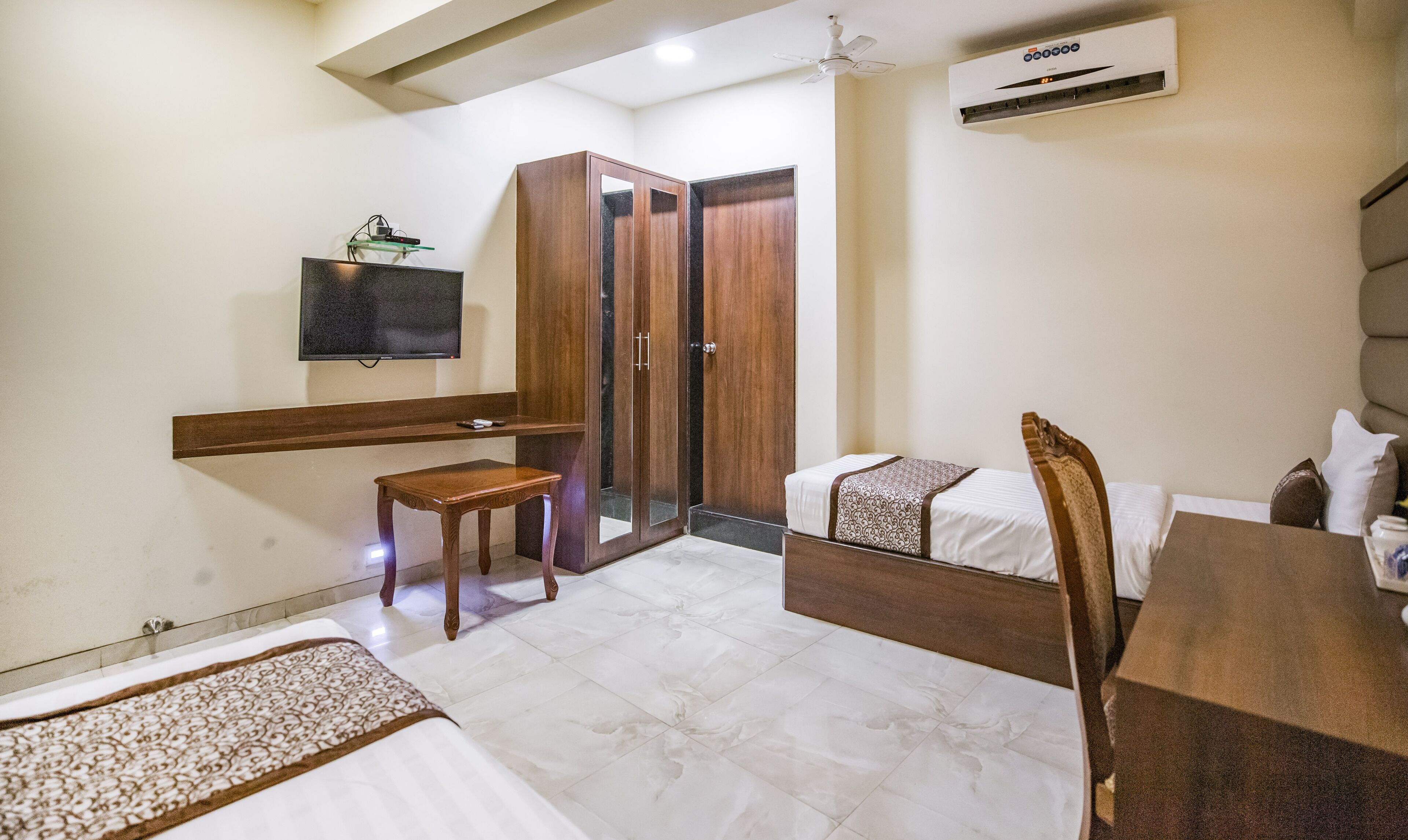 A hotel room with a bed, a desk, a chair, a television, and a wardrobe.