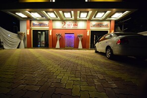 Hotel 2 Seven's elegant entrance features a prominent sign, beautiful flower arrangements, and a paved driveway.