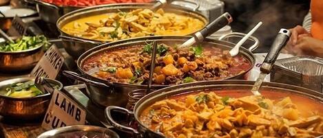 Un bufé con diversos platos señalizados, incluyendo curry de cordero y pollo.