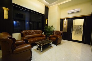 Relax in this stylish living area with a sofa, armchair, and coffee table, surrounded by a potted plant and large window.