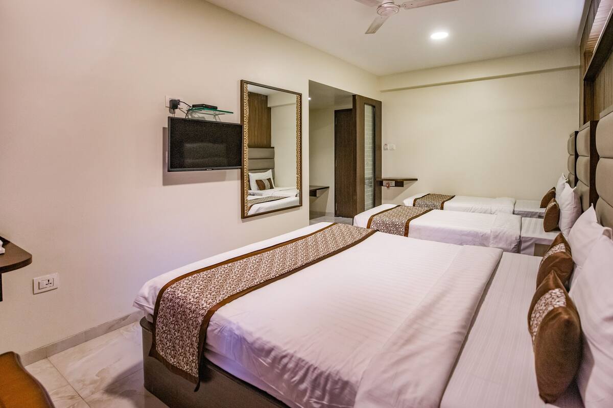 A hotel room with two beds, a TV, a mirror, and a ceiling fan.