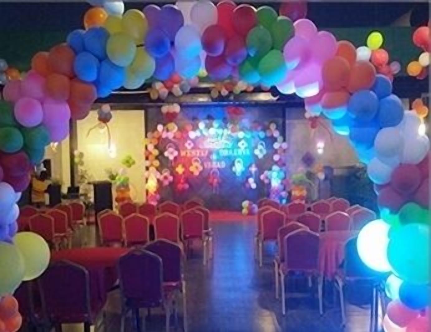A stage with a colorful balloon arch and a floral backdrop.