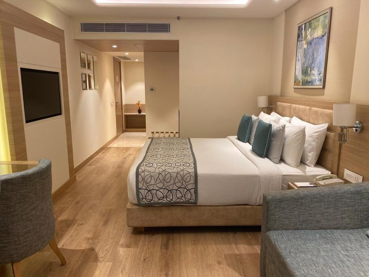 Una habitación de hotel con una cama grande, un escritorio, una silla y un televisor.