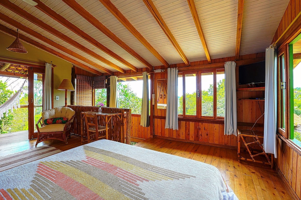 A wooden cabin with a large bed, a dining area, and a TV.