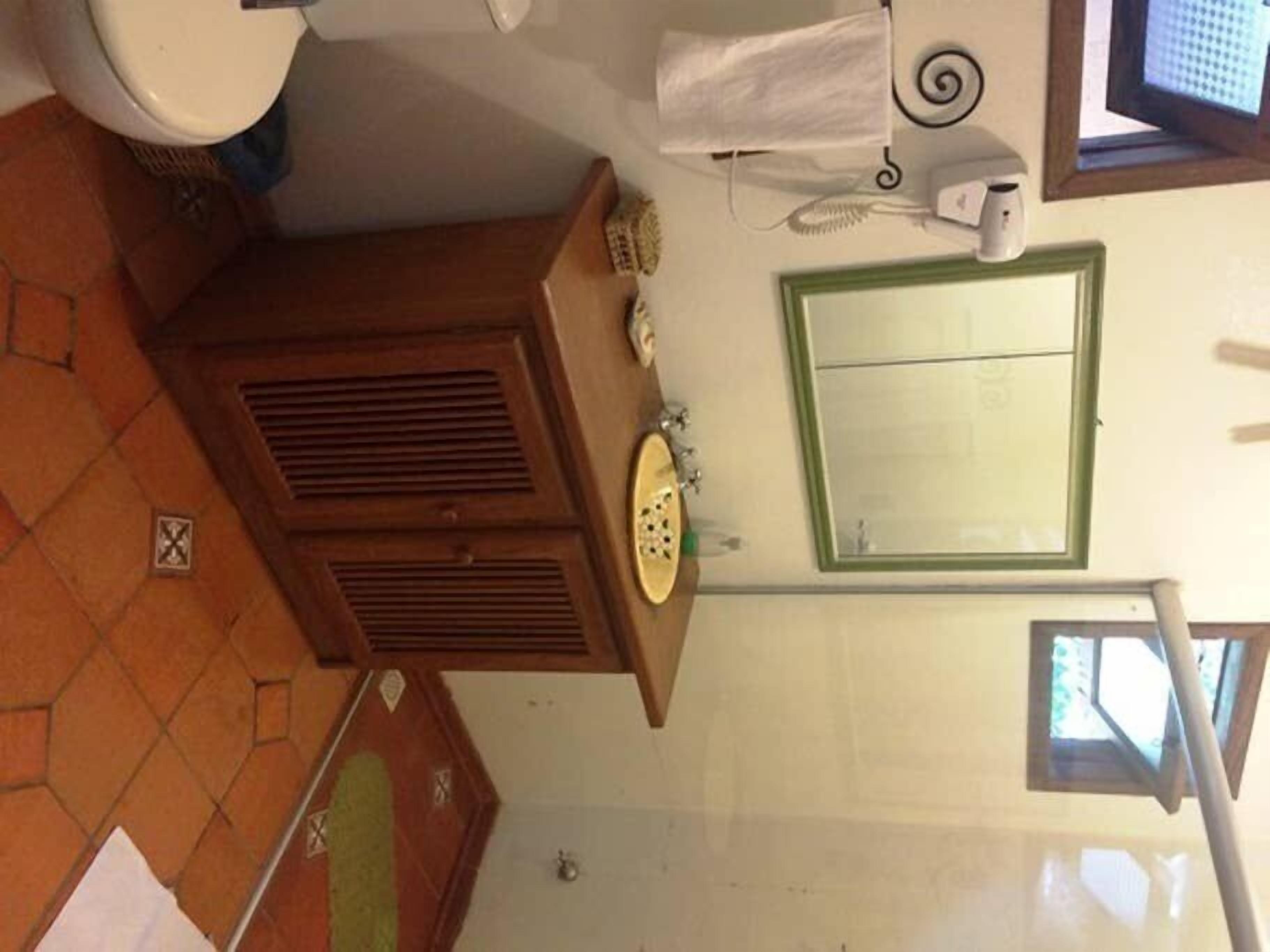 A bathroom with a toilet, a sink, a mirror, and a window.