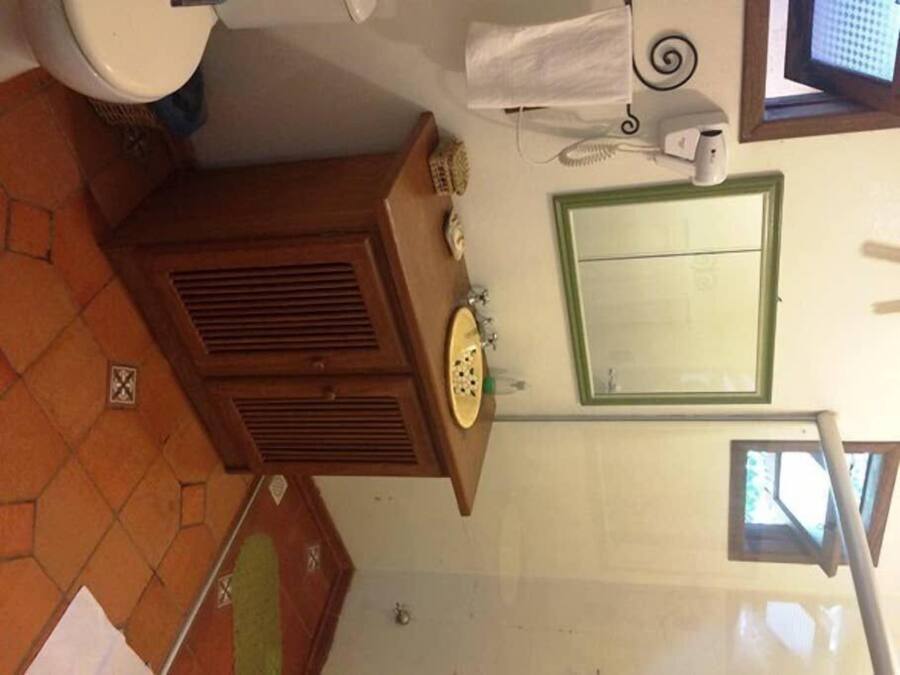 Une salle de bain avec des toilettes, un lavabo, un miroir et une fenêtre.