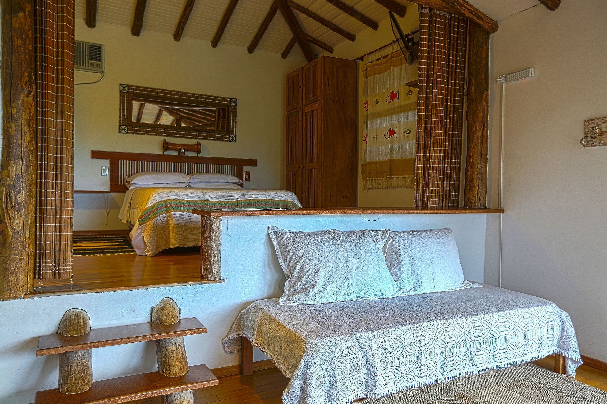 Un dormitorio con cama, un armario de madera, un espejo y una ventana con cortinas.