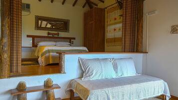 Un dormitorio con cama, un armario de madera, un espejo y una ventana con cortinas.