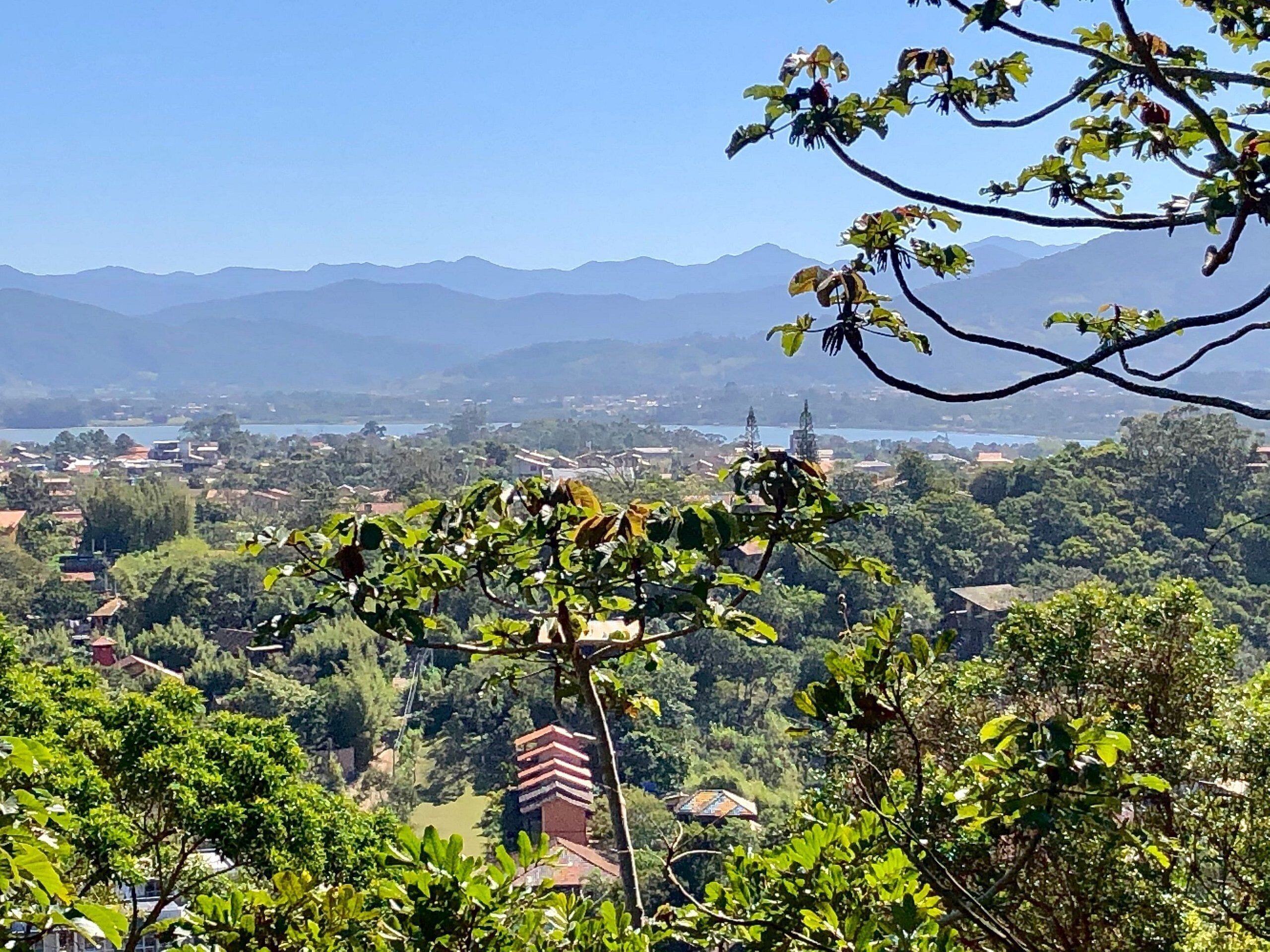 Vista panorámica de un paisaje montañoso con un pueblo y un lago al fondo.
