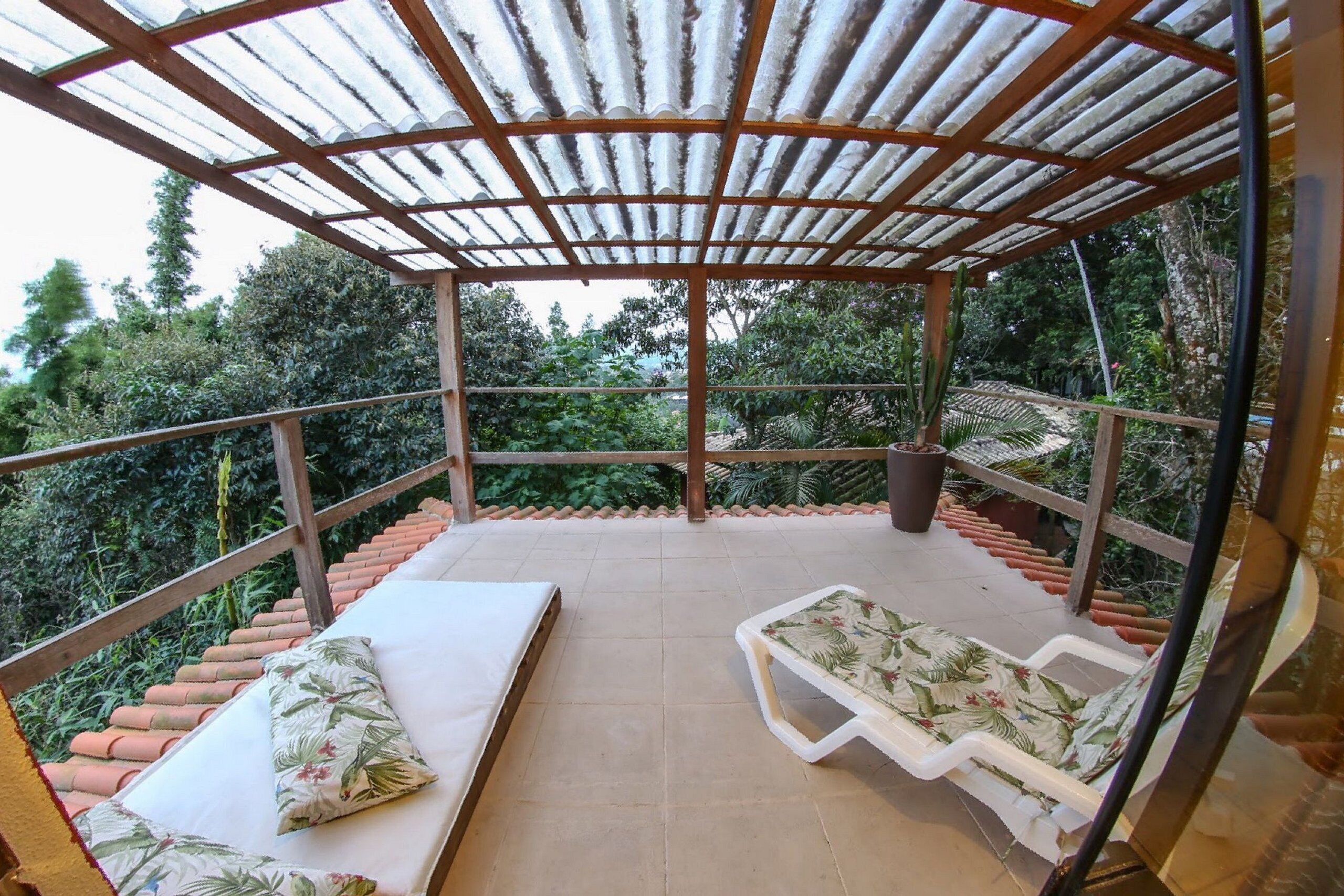 Un espacio de estar al aire libre techado con dos sillones reclinables y un colchón.