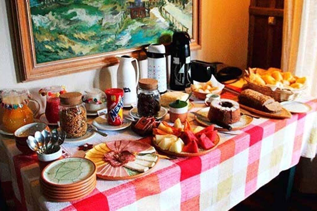 A breakfast table with various food items, a painting on the wall, and kitchen appliances.