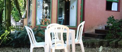 Un pequeño espacio al aire libre con mesa y sillas, rodeado de un jardín con plantas y un sendero de grava.