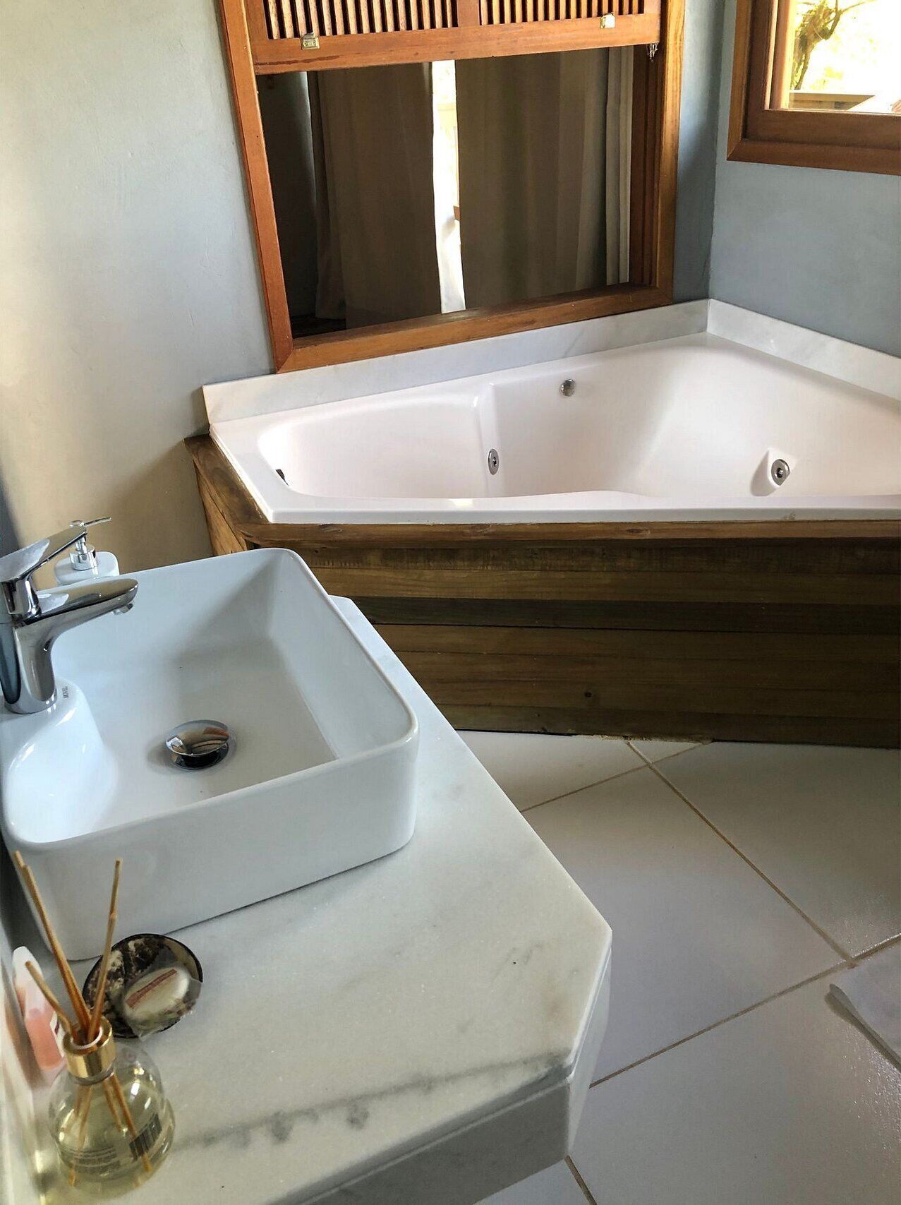 A bathroom with a white sink, a wooden bathtub, and a mirror above the sink.